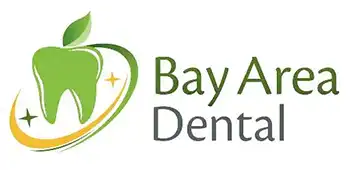 The image shows a logo with the text  BAY AREA DENTAL  prominently displayed above a graphic representation of a dental tooth, which is stylized with a green apple on top. Below the tooth, there s a circular emblem featuring a toothbrush and dental floss. The background is gray, and the overall style appears to be a digital graphic or logo design.