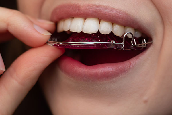 A person holding a toothbrush with dental floss wrapped around it.