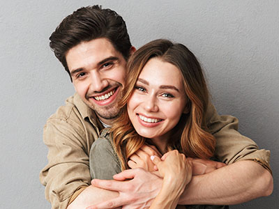 The image shows a man and woman hugging each other with smiles on their faces, suggesting a close relationship between them.