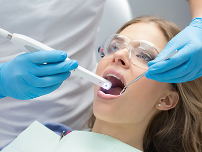 The image depicts a dental professional using an oral scanner on a patient s mouth during a dental examination.